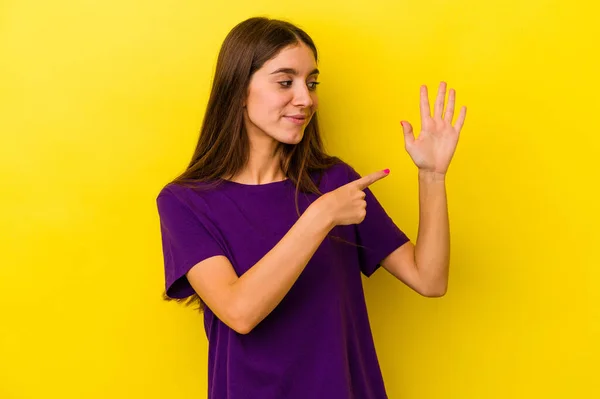 年轻的高加索女人在黄色背景上孤立无援 笑容满面 带着五号手指 — 图库照片