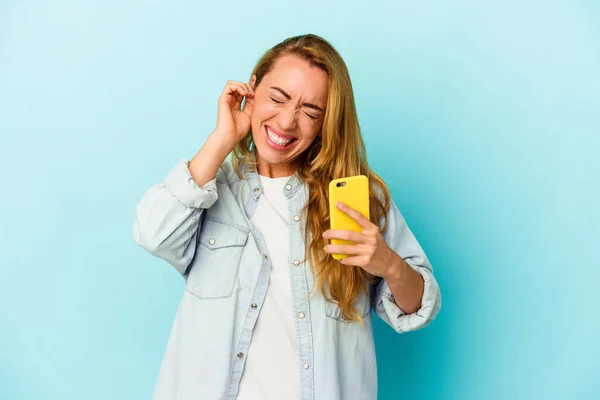 Kaukasisk Kvinna Som Håller Mobiltelefon Isolerad Blå Bakgrund Täcker Öron — Stockfoto