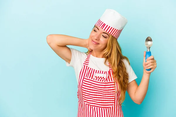 白人のアイスクリームメーカーの女性は 頭の後ろに触れる青い背景に隔離されたアイスクリームスクープを保持します 思考と選択をします — ストック写真
