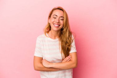 Kafkasyalı sarışın kadın pembe arka planda izole edilmiş gülüyor ve eğleniyor..