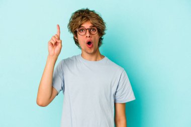 Mavi arka planda soyutlanmış beyaz makyajlı genç bir adamın bir fikri, ilham verici bir konsepti var..