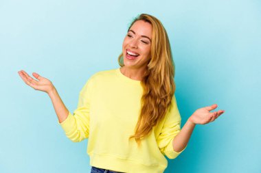 Beyaz kadın, mavi arka planda izole edilmiş neşeli bir şekilde gülüyor. Mutluluk kavramı.