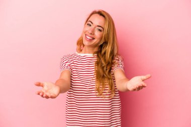 Pembe arka planda izole edilmiş beyaz sarışın kadın hoş bir yüz ifadesi sergiliyor..