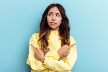 Mavi arka plan noktalarında izole edilmiş genç Meksikalı kadın iki seçenek arasında seçim yapmaya çalışıyor..