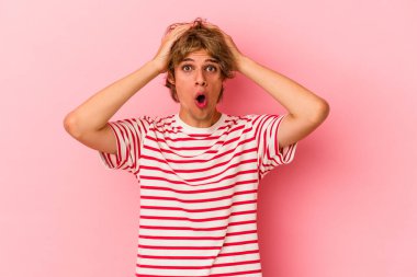 Makyajlı beyaz bir adam pembe arka planda izole edilmiş, şaşırmış ve şok olmuş..