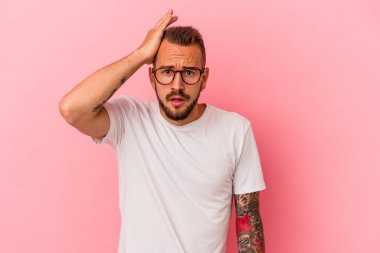 Pembe arka planda dövmeleri olan genç beyaz adam şoka uğruyor, önemli bir toplantıyı hatırlıyor..