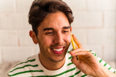 Genç melez adam koltuğunda telefonla konuşuyor.