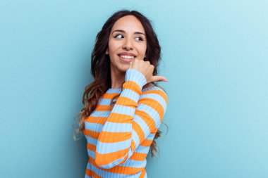 Genç Meksikalı kadın mavi arka planda izole edilmiş başparmak uzakta, gülüyor ve kaygısız.