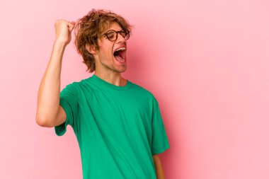 Pembe arka planda soyutlanmış beyaz tenli genç bir adam zaferi, tutkuyu ve coşkuyu kutluyor, mutlu bir ifade..