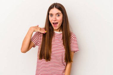 Beyaz arka planda izole edilmiş genç beyaz bir kadın bir şeye gülüyor, elleriyle ağzını kapatıyor..