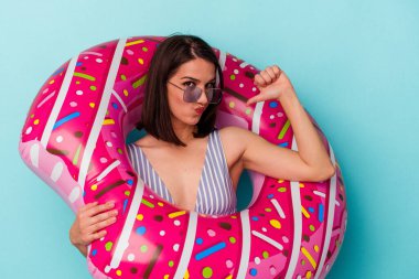 Mavi arka planda izole edilmiş şişme donutu olan genç beyaz kadın gururlu ve kendinden emin hissediyor, örnek olarak.