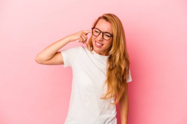 Pembe arka planda izole edilmiş, elleri kulaklarında beyaz sarışın kadın..