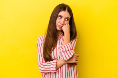 Sarı arka planda izole edilmiş, üzgün ve dalgın hisseden, kopyalama alanına bakan beyaz bir kadın..