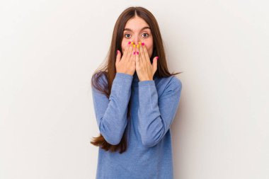 Beyaz arka planda izole edilmiş genç beyaz kadın şok olmuş, elleri ağızda, yeni bir şey keşfetmeye hevesli..