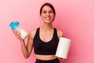 Pembe arka planda izole edilmiş protein içeceği içen beyaz bir kadın.