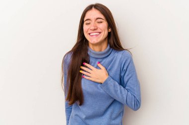 Beyaz arka planda izole genç beyaz kadın yüksek sesle gülüyor elini göğsüne koyuyor..