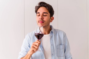 Genç melez adam mutfakta şarap içiyor.