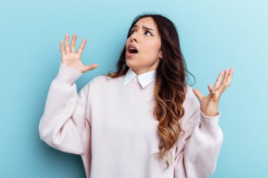 Mavi arka planda izole edilmiş genç Meksikalı kadın gökyüzüne haykırıyor, yukarı bakıyor, hayal kırıklığına uğramış..