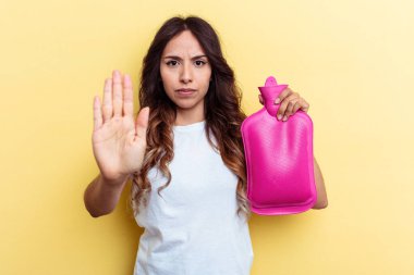Sarı arka planda izole edilmiş sıcak bir çanta taşıyan genç melez kadın elini uzatmış, dur işaretini göstererek seni engelliyor..