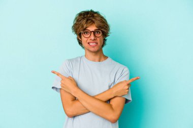 Mavi arka plan noktalarında izole edilmiş beyaz makyajlı genç bir adam iki seçenek arasında seçim yapmaya çalışıyor..