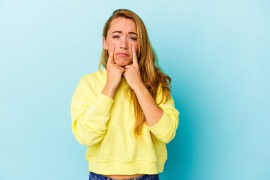 Beyaz kadın mavi arka planda izole edilmiş, ağlıyor, bir şeyden memnun değil, acı ve kafa karışıklığı kavramı..