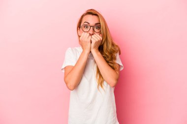 Pembe arka planda izole edilmiş, tırnak yiyen, gergin ve endişeli beyaz bir kadın..