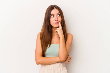 Beyaz arka planda soyutlanmış beyaz tenli genç bir kadın şüpheli ve şüpheci bir ifadeyle yana bakıyor..