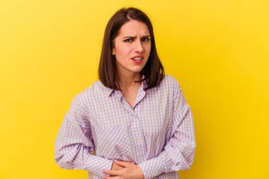 Sarı arka planda karaciğer ağrısı çeken, karnı ağrıyan beyaz bir kadın..