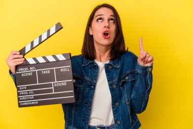 Sarı arka planda izole edilmiş, ağzı açık, üst tarafı gösteren bir klaket tutan beyaz kadın..