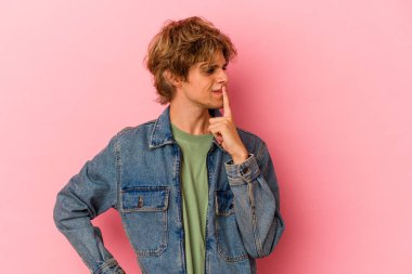 Pembe arka planda soyutlanmış beyaz makyajlı genç bir adam ya sır saklıyor ya da sessizlik istiyor..