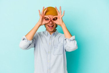 Makyajlı genç beyaz adam mavi arka planda izole edilmiş, heyecanlı..