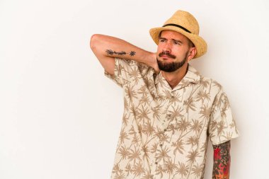 Beyaz arka planda izole edilmiş yaz kıyafetleri giyen, kafasının arkasına dokunan, düşünen ve bir seçim yapan beyaz dövmeli genç beyaz bir adam..