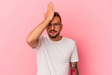 Pembe arka planda izole edilmiş, alnına avuç içi ve kapalı gözlerle tokat atan, bir şeyi unutan, beyaz, genç bir adam..