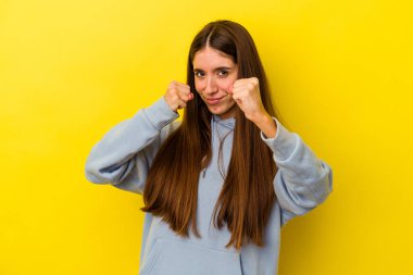 Sarı arka planda izole edilmiş genç beyaz kadın bir tartışma yüzünden yumruk, öfke, kavga ve boks atıyor..