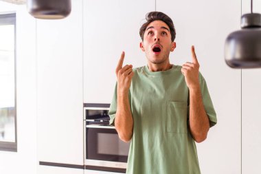 Genç melez adam mutfağında ağzı açık bir şekilde üst tarafı işaret ediyor..