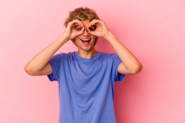 Makyajlı beyaz bir adam pembe arka planda izole edilmiş. Gözlerinde iyi bir işaret var.