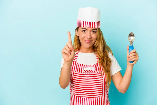 コーカシアのアイスクリームメーカー女性を保持していますアイスクリームスクープ隔離上の青背景ショーナンバーワンとともに指 — ストック写真