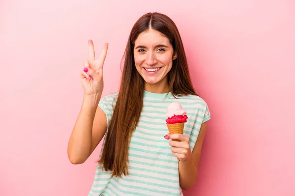 若いですCaucasian女性を持っていますアイスを持っていますピンクの背景に隔離された番号2とともに指 — ストック写真