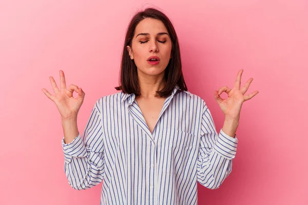 Pembe arka planda izole edilmiş genç beyaz kadın sıkı çalışma gününden sonra dinleniyor, yoga yapıyor..