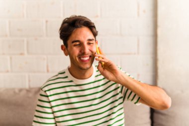 Genç melez adam koltuğunda telefonla konuşuyor.