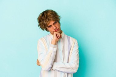 Mavi arka planda soyutlanmış beyaz makyajlı genç bir adam tekrarlanan bir görevden yoruldu..