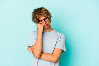 Mavi arka planda soyutlanmış, sıkılmış, yorgun ve dinlenmeye ihtiyacı olan beyaz, genç bir adam..