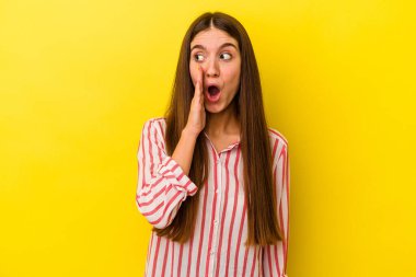 Sarı arka planda izole edilmiş genç beyaz kadın gizli bir sıcak fren haberi veriyor ve yana bakıyor.