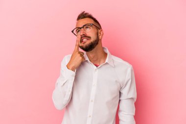 Pembe arka planda izole edilmiş dövmeleri olan genç, beyaz bir adam ağlıyor, bir şeyden mutsuz, acı ve kafa karışıklığı konsepti var..