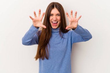 Beyaz arka planda izole edilmiş genç beyaz kadın pençelerini kedi taklidi yaparken gösteriyor, agresif bir hareket..