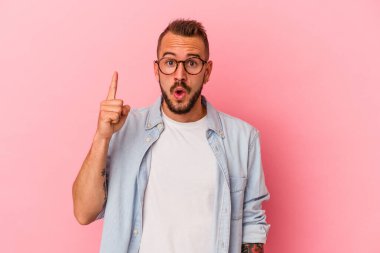 Pembe arka planda izole edilmiş dövmeleri olan genç beyaz bir adam. Bir fikri var, ilham verici bir kavram..