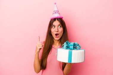 Pembe arka planda izole edilmiş, ağzı açık, beyaz bir kadın doğum gününü kutluyor..