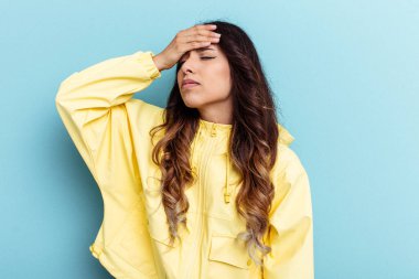 Mavi arka planda izole edilmiş genç Meksikalı kadın tapınaklara dokunuyor ve baş ağrısı çekiyor..