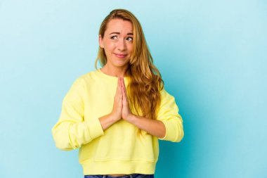 Beyaz kadın mavi arka planda izole edilmiş dua ediyor, bağlılık gösteriyor, dindar biri ilahi ilham arıyor..