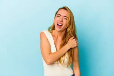 Beyaz kadın, mavi arka planda izole edilmiş, omuz ağrısı var..